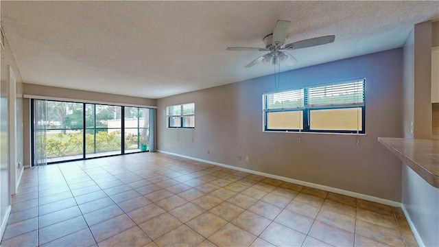 spare room featuring light tile patterned floors, a textured ceiling, and ceiling fan