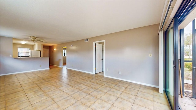 spare room featuring a healthy amount of sunlight, ceiling fan, and light tile patterned flooring