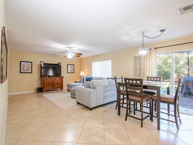 tiled dining room with ceiling fan with notable chandelier