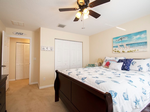 bedroom with a textured ceiling, light colored carpet, ceiling fan, and a closet