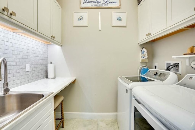 laundry area with light tile patterned floors, a sink, baseboards, washer and dryer, and cabinet space