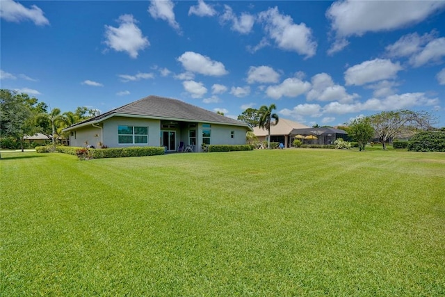 rear view of property with a yard and stucco siding