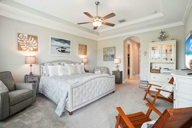 bedroom featuring arched walkways, a tray ceiling, crown molding, light colored carpet, and visible vents