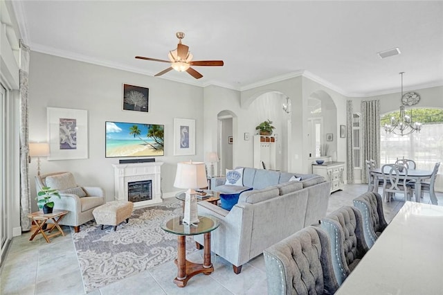 living room with ornamental molding, arched walkways, ceiling fan with notable chandelier, and a glass covered fireplace