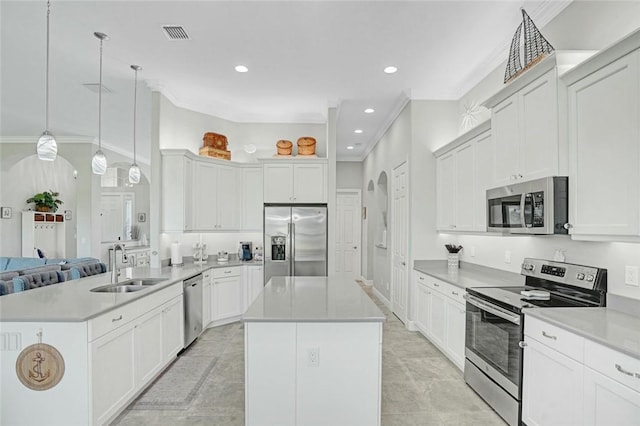 kitchen with a sink, stainless steel appliances, a peninsula, a kitchen island, and ornamental molding