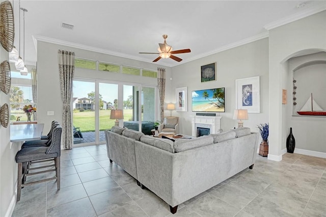 living room featuring visible vents, ceiling fan, baseboards, a glass covered fireplace, and ornamental molding