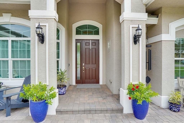 view of exterior entry with covered porch and stucco siding