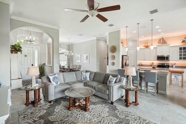 living area featuring arched walkways, ornamental molding, light tile patterned flooring, and visible vents