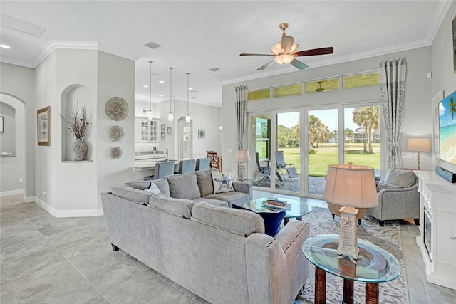 living area featuring recessed lighting, crown molding, a ceiling fan, baseboards, and arched walkways