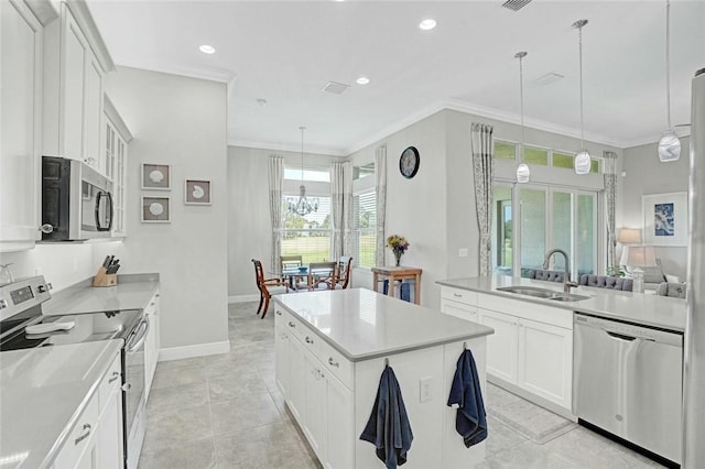 kitchen featuring a sink, a center island, crown molding, baseboards, and appliances with stainless steel finishes
