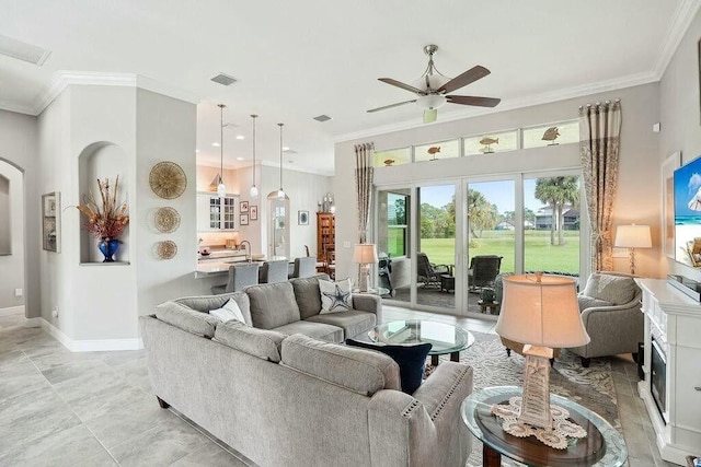 living room featuring baseboards, ceiling fan, visible vents, and crown molding