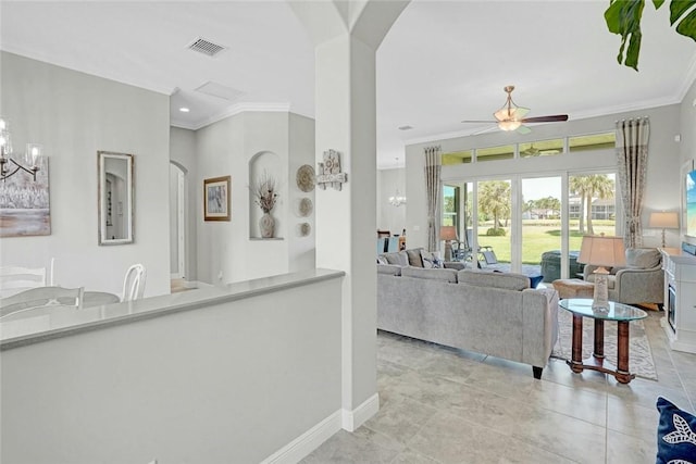 living room with arched walkways, ceiling fan with notable chandelier, baseboards, visible vents, and crown molding