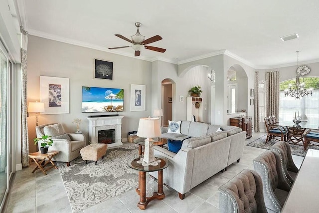 living room featuring arched walkways, ornamental molding, a glass covered fireplace, and visible vents