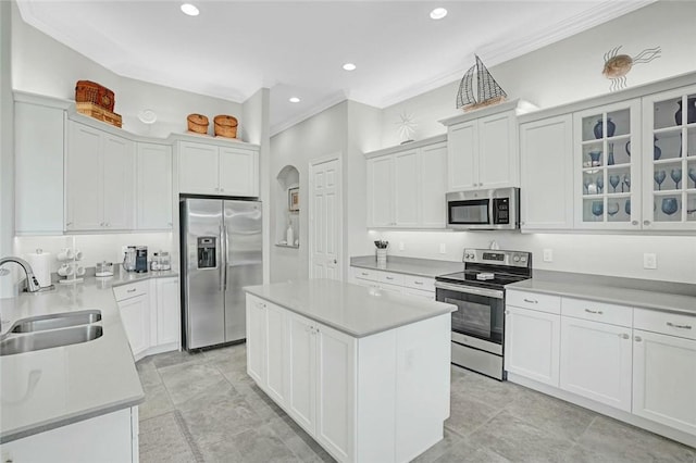 kitchen featuring stainless steel appliances, crown molding, a kitchen island, and a sink