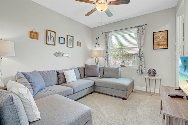 living room with baseboards, light carpet, and a ceiling fan