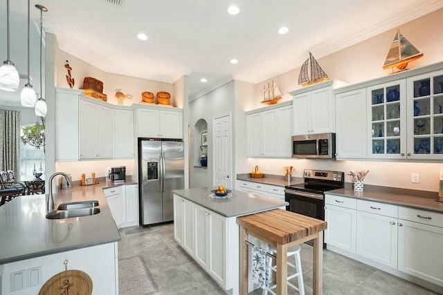 kitchen featuring crown molding, appliances with stainless steel finishes, arched walkways, and a sink