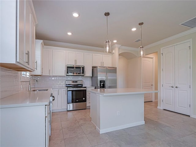 5190 Unity Sq, Vero Beach, FL 32967 - kitchen with appliances with stainless steel finishes, crown molding, decorative backsplash, white cabinetry, and a center island