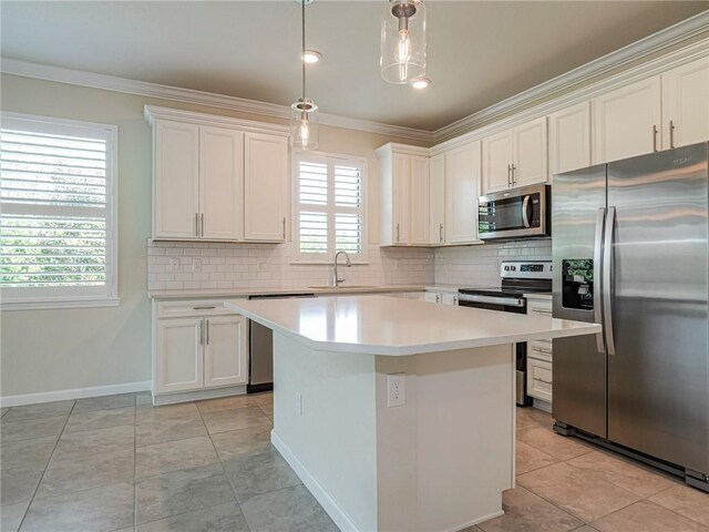 5190 Unity Sq, Vero Beach, FL 32967 - kitchen featuring appliances with stainless steel finishes, ornamental molding, white cabinetry, decorative backsplash, and a kitchen island