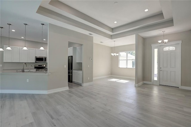 7985 99th Ave, Vero Beach, FL 32967 - entrance foyer with a chandelier, a tray ceiling, light wood finished floors, and recessed lighting
