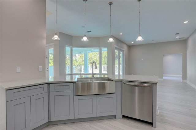 7985 99th Ave, Vero Beach, FL 32967 - kitchen with stainless steel dishwasher, light wood-style floors, gray cabinets, light countertops, and hanging light fixtures
