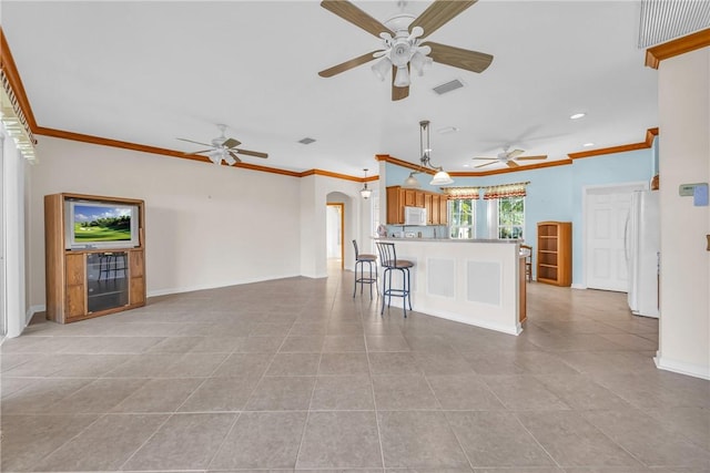 unfurnished living room with arched walkways, a ceiling fan, baseboards, and ornamental molding