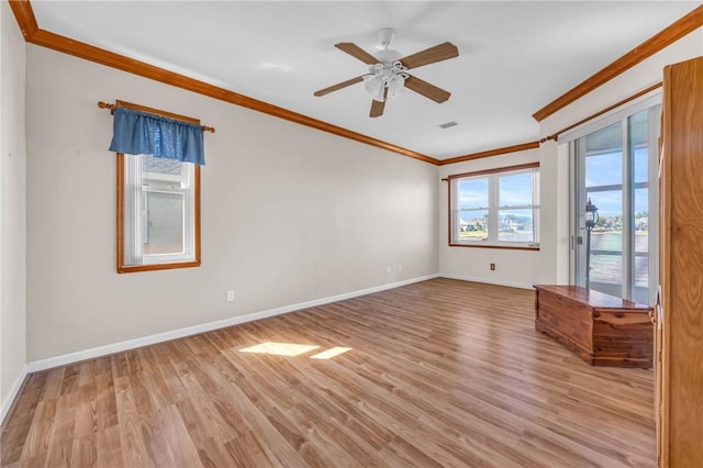 empty room with visible vents, wood finished floors, baseboards, and ornamental molding