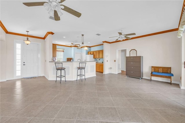 kitchen featuring a breakfast bar, freestanding refrigerator, a peninsula, light tile patterned floors, and baseboards