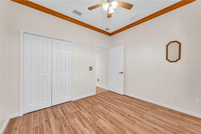 unfurnished bedroom featuring visible vents, baseboards, ornamental molding, light wood-style floors, and a closet