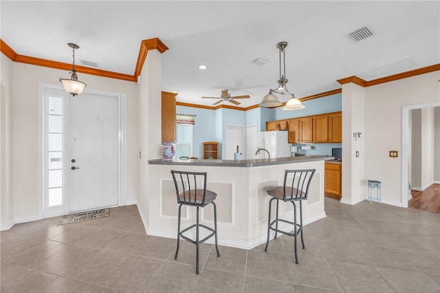 kitchen featuring a breakfast bar, crown molding, and freestanding refrigerator