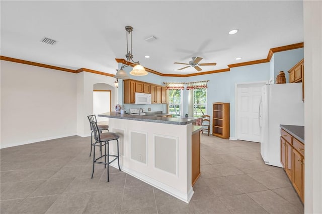 kitchen featuring white appliances, dark countertops, visible vents, and arched walkways