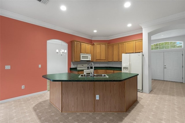 kitchen featuring sink, a notable chandelier, white appliances, a center island with sink, and ornamental molding