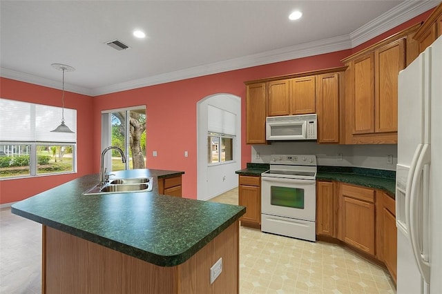 kitchen featuring sink, hanging light fixtures, crown molding, white appliances, and a kitchen island with sink