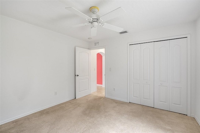 unfurnished bedroom featuring ceiling fan, light carpet, and a closet