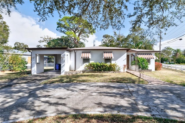 ranch-style home featuring a carport and a front yard