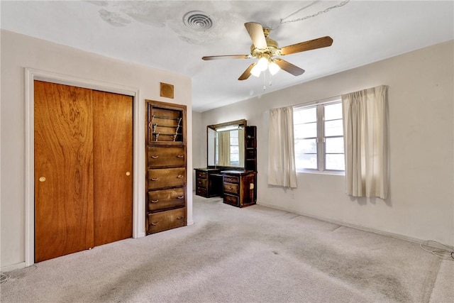 unfurnished bedroom featuring ceiling fan, light carpet, and a closet