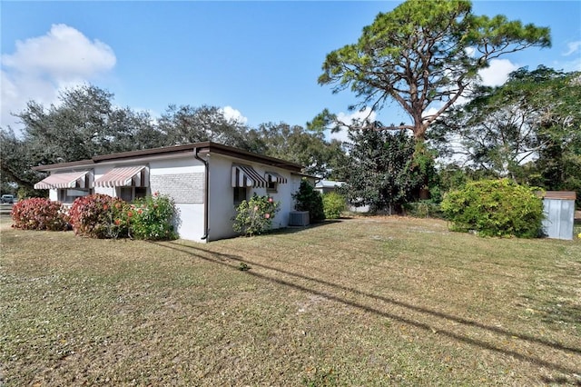 view of side of property with central AC unit and a yard