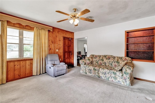 living room featuring light carpet, ceiling fan, and wood walls