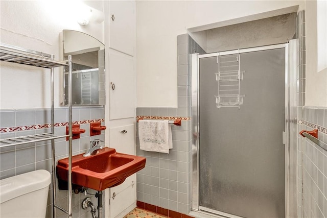 bathroom featuring sink, toilet, tile walls, and walk in shower