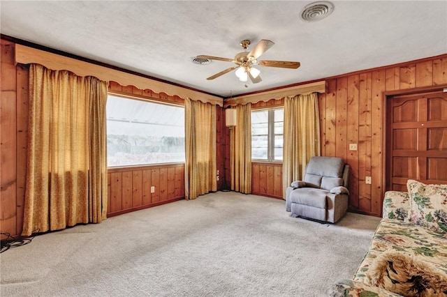 unfurnished room featuring light carpet, ceiling fan, wood walls, and ornamental molding