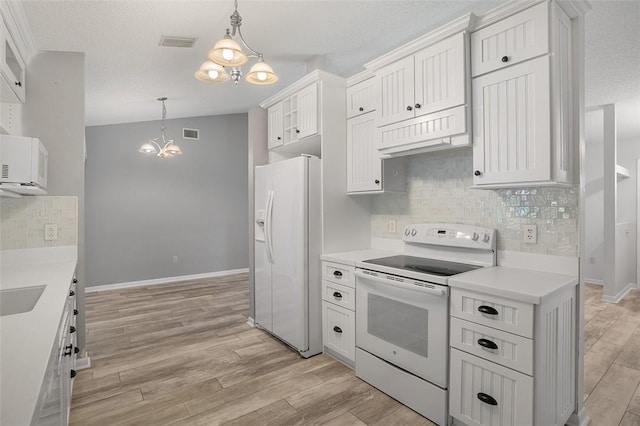 kitchen with pendant lighting, white appliances, white cabinets, and an inviting chandelier