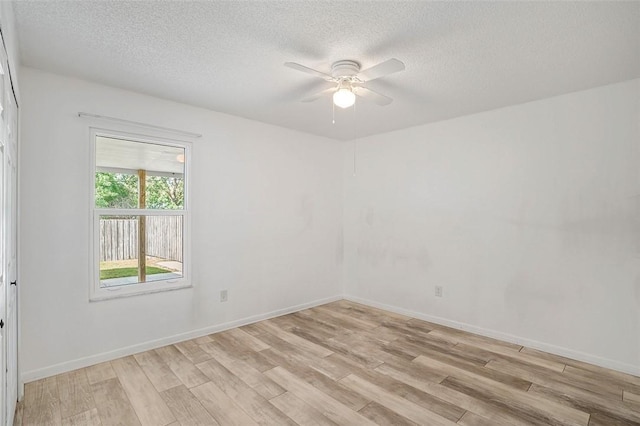 empty room with ceiling fan, light hardwood / wood-style flooring, and a textured ceiling