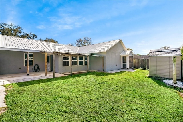 rear view of house with a patio, a yard, and a storage shed