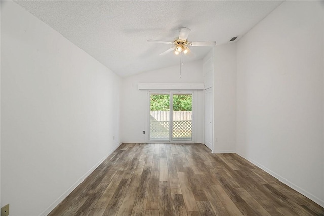 unfurnished room featuring ceiling fan, dark hardwood / wood-style flooring, vaulted ceiling, and a textured ceiling