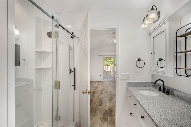 bathroom featuring vanity, hardwood / wood-style floors, a shower with shower door, and lofted ceiling