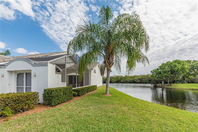 exterior space with a lanai, a lawn, and a water view