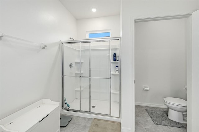 bathroom featuring tile patterned flooring, toilet, and a shower with door