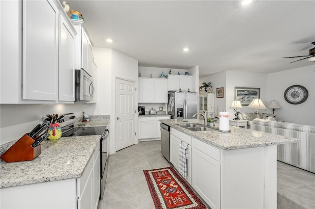 kitchen featuring appliances with stainless steel finishes, white cabinetry, a kitchen island with sink, and sink