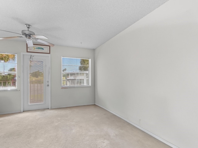 spare room featuring ceiling fan, a textured ceiling, and light carpet