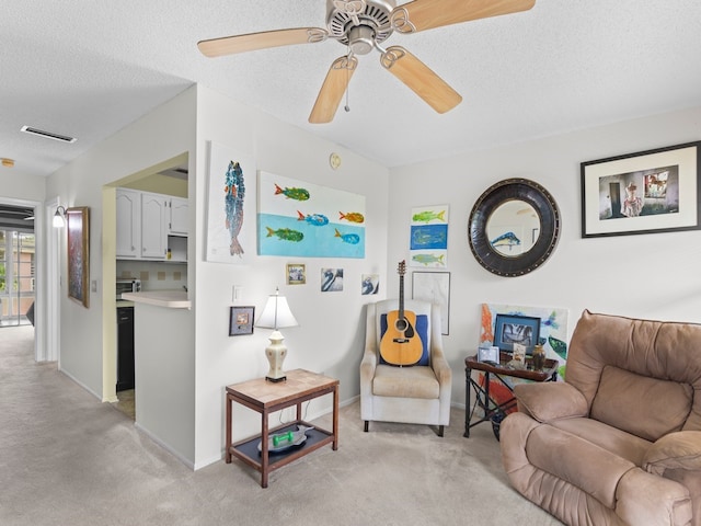 living room featuring ceiling fan, a textured ceiling, and light colored carpet