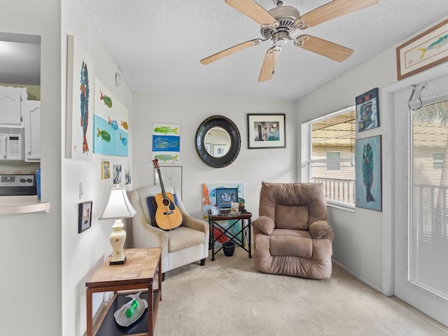 sitting room featuring ceiling fan, a textured ceiling, and light carpet